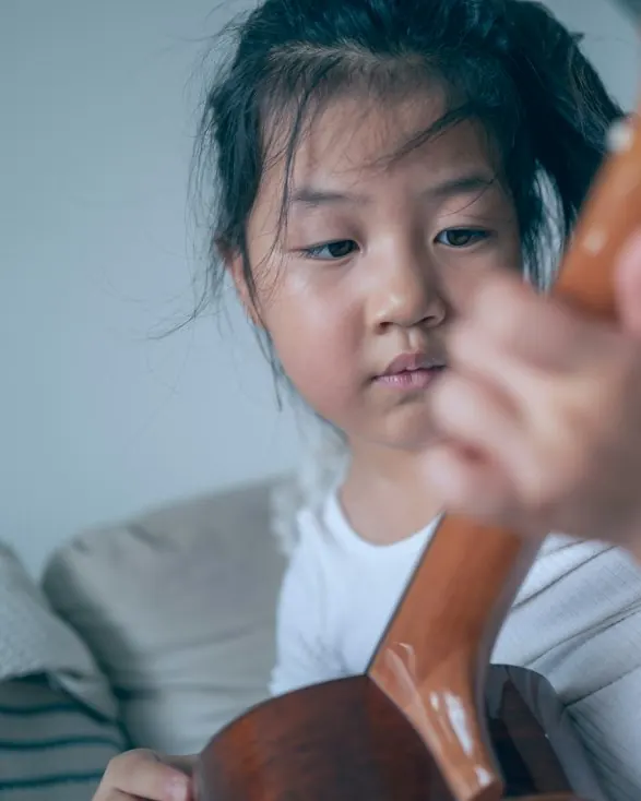A girl looking down at the guitar she is holding.